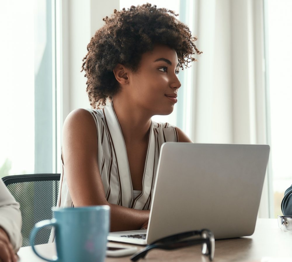 She loves her work. Beautiful african woman sitting at business meeting and smiling